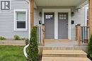 Light grey siding exterior featuring two entry doors with upper window panels and dark grey finishes, each with an adjacent wall-mounted light fixture and mailbox - 47 New Street, Hamilton, ON  - Outdoor With Exterior 