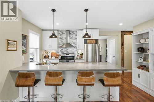 Modern kitchen featuring a large island with seating, stainless steel appliances, white cabinetry, and a mosaic tile backsplash - 47 New Street, Hamilton, ON - Indoor Photo Showing Kitchen With Double Sink With Upgraded Kitchen