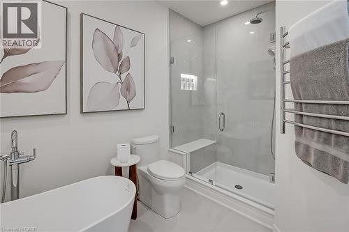 Bathroom featuring a freestanding soaking tub with floor-mounted faucet, a frameless glass shower enclosure with built-in bench and recessed niche, and a wall-mounted towel warmer - 4285 Couples Crescent, Burlington, ON - Indoor Photo Showing Bathroom