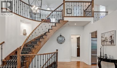 Grand curved staircase featuring wood treads, wrought iron balusters, and a patterned runner - 4285 Couples Crescent, Burlington, ON - Indoor Photo Showing Other Room