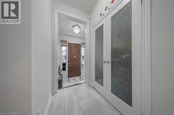 Foyer entry featuring light-toned large format tile flooring and a brown arched panel front door - 