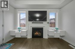 Living area with wood-finish flooring, a contemporary fireplace with a classic white mantel, and two large windows - 