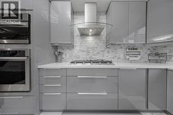Modern kitchen featuring glossy grey cabinetry and stainless steel appliances - 
