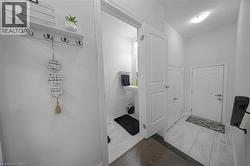 Well-lit entryway featuring a white paneled door, light tile flooring, and a powder room with a pedestal sink - 