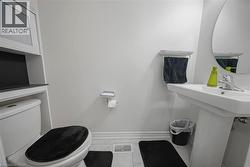Powder room featuring a pedestal sink with chrome faucet, an oval wall mirror, and a wall-mounted towel rack - 