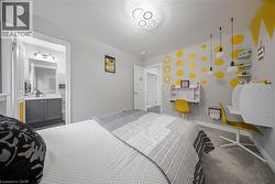 Carpeted bedroom featuring a built-in desk, wall-mounted shelving, and a modern ceiling light fixture - 