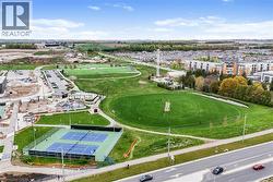 Expansive community park featuring a large green space, multiple sports fields, tennis courts, and a water play area - 