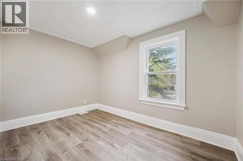 Room featuring wood-finish flooring, neutral wall paint, white baseboards, and a double-hung window with white trim - 15 Gordon Avenue, Kitchener, ON - Indoor Photo Showing Other Room