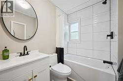 Bathroom featuring a white vanity with gold-tone hardware, a circular mirror, and matte black plumbing fixtures - 
