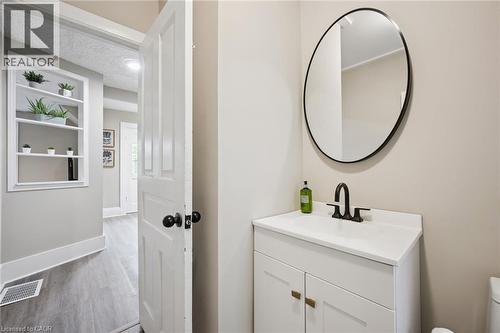 Bathroom vanity featuring a white countertop, matte black faucet, and round black-framed mirror - 15 Gordon Avenue, Kitchener, ON - Indoor Photo Showing Bathroom