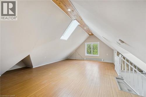 Expansive attic space featuring wood-finish flooring, a prominent skylight, and a window with exterior views - 15 Gordon Avenue, Kitchener, ON - Indoor Photo Showing Other Room
