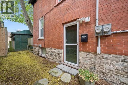 Red brick exterior with a natural stone foundation, featuring a white storm door entryway - 15 Gordon Avenue, Kitchener, ON - Outdoor With Exterior