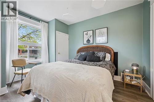 Bedroom featuring wood-finish flooring, a contemporary ceiling fan, and a window with white curtains - 15 Gordon Avenue, Kitchener, ON - Indoor Photo Showing Bedroom