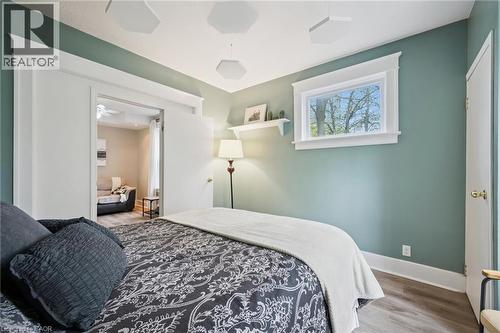 Bedroom featuring light wood-finish flooring, a window with white trim, and a doorway opening to an additional room - 15 Gordon Avenue, Kitchener, ON - Indoor Photo Showing Bedroom