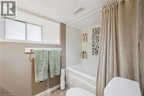 Bathroom featuring a white bathtub, decorative accent tile, and a privacy window - 15 Gordon Avenue, Kitchener, ON - Indoor Photo Showing Bathroom