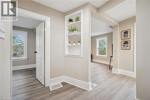 Light wood-finish flooring throughout, featuring a built-in shelving unit, white trim, and a paneled interior door - 15 Gordon Avenue, Kitchener, ON - Indoor Photo Showing Other Room
