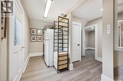 Hallway featuring wood-finish flooring, white trim, and neutral wall tones - 