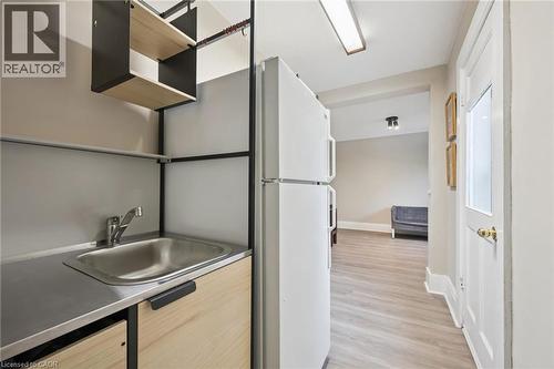 Compact kitchenette featuring a stainless steel sink, wood-finish cabinetry, and open shelving - 15 Gordon Avenue, Kitchener, ON - Indoor