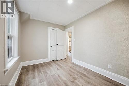 Light wood-finish flooring complements neutral wall tones and white trim - 15 Gordon Avenue, Kitchener, ON - Indoor Photo Showing Other Room