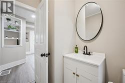 Bathroom vanity featuring a white countertop, matte black faucet, and round black-framed mirror - 