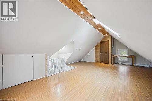Spacious attic area featuring wood-finish flooring, a white spindle railing, and a window for natural light - 15 Gordon Avenue, Kitchener, ON - Indoor Photo Showing Other Room