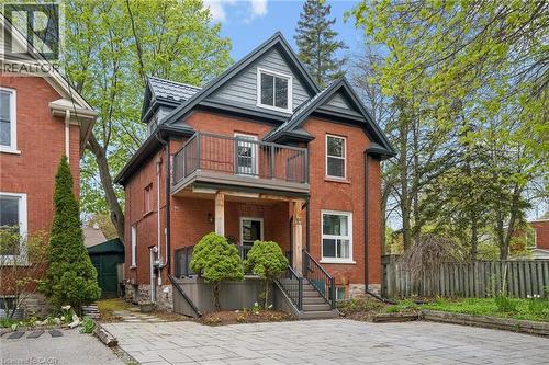 Brick exterior with a metal roof accent, second-story balcony with metal railings, and a ground-level covered porch - 15 Gordon Avenue, Kitchener, ON - Outdoor