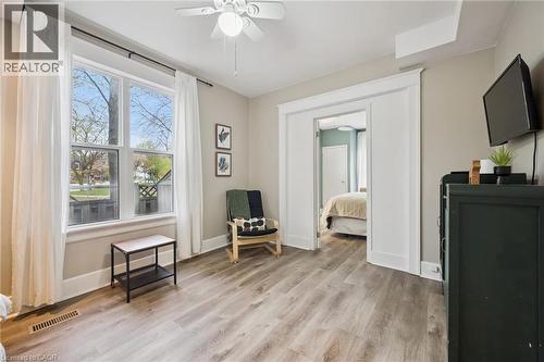 Spacious room featuring wood-finish flooring, a large window with white trim, and a ceiling fan - 15 Gordon Avenue, Kitchener, ON - Indoor