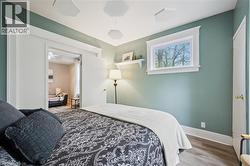 Bedroom featuring light wood-finish flooring, a window with white trim, and a doorway opening to an additional room - 