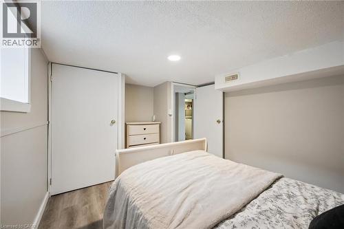 Bedroom featuring light gray walls, recessed lighting, a window with white trim, wood-finish flooring, and white interior doors - 15 Gordon Avenue, Kitchener, ON - Indoor Photo Showing Bedroom