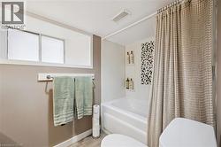 Bathroom featuring a white bathtub, decorative accent tile, and a privacy window - 