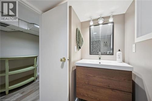 Bathroom featuring a wood-finish vanity with an integrated white sink, a rectangular mirror, and track lighting - 15 Gordon Avenue, Kitchener, ON - Indoor Photo Showing Bathroom