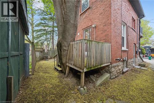 Red brick exterior with stone foundation detailing, featuring a wooden deck with railing, and a private side yard - 15 Gordon Avenue, Kitchener, ON - Outdoor With Exterior