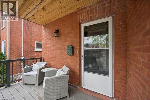 Front porch featuring a durable composite deck, black metal railing, and a wood-paneled ceiling - 15 Gordon Avenue, Kitchener, ON - Outdoor With Deck Patio Veranda With Exterior