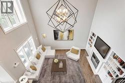 Vaulted living room with a geometric chandelier, hardwood flooring, and a built-in media center with shelving surrounding a fireplace - 