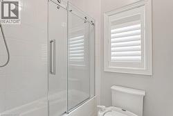 Bathtub with clear glass sliding shower doors and white subway tile surround - 