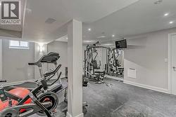 Dedicated fitness area featuring durable rubber mat flooring, recessed ceiling lighting, a wall-mounted television, and a full-height mirror panel - 