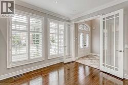 Interior space featuring rich wood-finish flooring and multiple windows with white plantation shutters - 