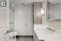 Bathroom vanity featuring a polished chrome faucet, under-mount sink, and white countertop with subtle veining - 