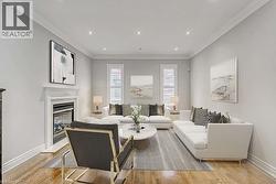 Living area featuring wood-finish flooring, a white mantel fireplace, and recessed lighting - 