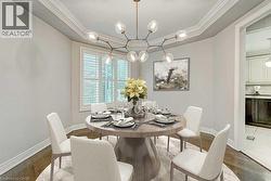 Elegant dining area featuring a contemporary chandelier, crown molding, and wood-finish flooring - 