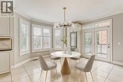 Bright dining area featuring a modern chandelier, bay window with plantation shutters, double glass panel doors, integrated refrigerator, and large format tile flooring - 