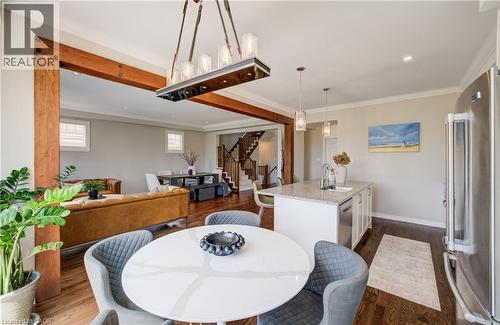 Open-concept living space featuring wood-finish flooring, exposed wood beams, a central kitchen island with a stone countertop, stainless steel appliances, and a staircase with wood treads and white r - 19 Shoreacres Drive, Kitchener, ON - Indoor Photo Showing Dining Room
