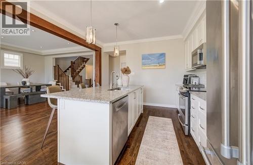 Kitchen featuring a central island with granite countertop, stainless steel appliances, white cabinetry, and wood-finish flooring - 19 Shoreacres Drive, Kitchener, ON - Indoor Photo Showing Kitchen With Stainless Steel Kitchen With Upgraded Kitchen
