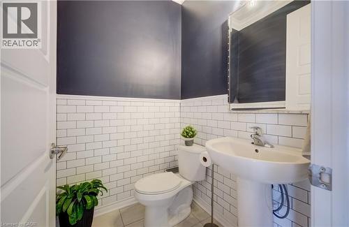 Pedestal sink with chrome faucet, subway tile wainscoting, and a wall-mounted mirror - 19 Shoreacres Drive, Kitchener, ON - Indoor Photo Showing Bathroom