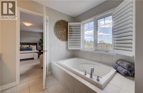 Soaking tub with a tiled surround, chrome fixtures, and plantation shutters - 19 Shoreacres Drive, Kitchener, ON - Indoor Photo Showing Bathroom