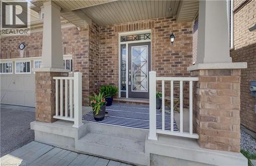 Brick facade with a covered porch featuring white railings, concrete steps, and a decorative glass front door - 19 Shoreacres Drive, Kitchener, ON - Outdoor