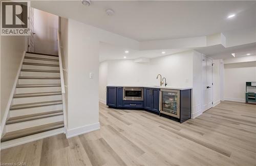 Finished lower level featuring light wood-finish flooring, recessed lighting, and a built-in wet bar with dark cabinetry, integrated microwave, and beverage refrigerator - 19 Shoreacres Drive, Kitchener, ON - Indoor Photo Showing Other Room With Fireplace