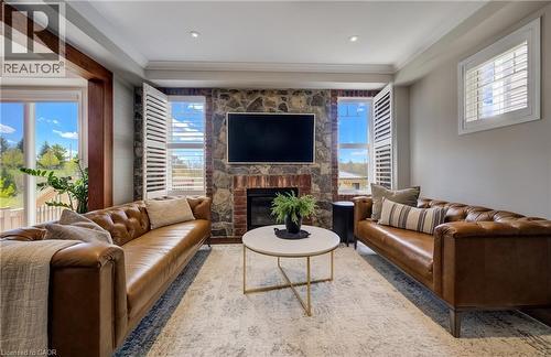 Living area featuring a stone and brick fireplace with an integrated hearth, white plantation shutters, and recessed lighting - 19 Shoreacres Drive, Kitchener, ON - Indoor Photo Showing Living Room With Fireplace