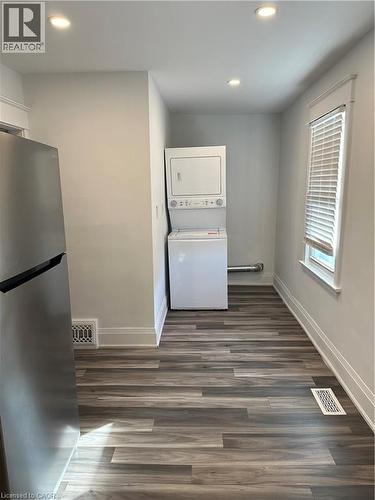Clothes washing area featuring stacked washer / dryer and dark wood-type flooring - 1090 Cannon Street E, Hamilton, ON - Indoor