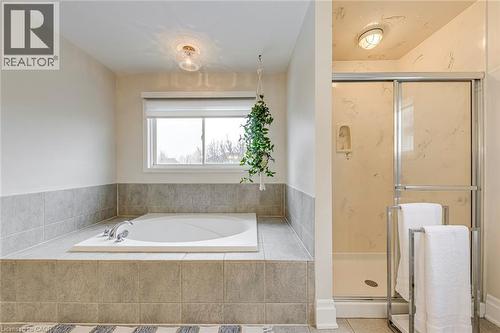 Bathroom featuring a built-in bathtub with tiled surround, a window with a roller blind, and a glass-enclosed shower - 4267 Sarazen Drive, Burlington, ON - Indoor Photo Showing Bathroom